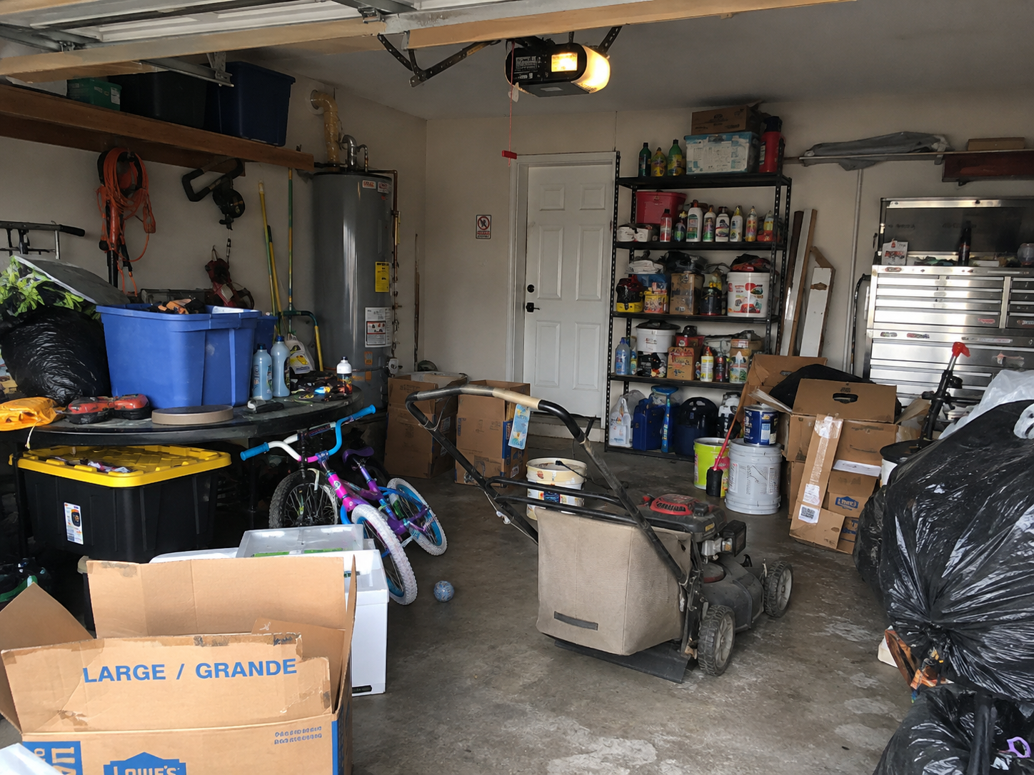A garage full of boxes, equipment, bicycles, and household items before a Bauman Bounty clearout