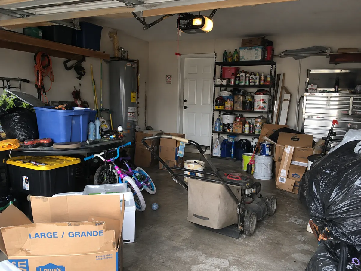 A garage full of boxes, equipment, bicycles, and household items before a Bauman Bounty clearout